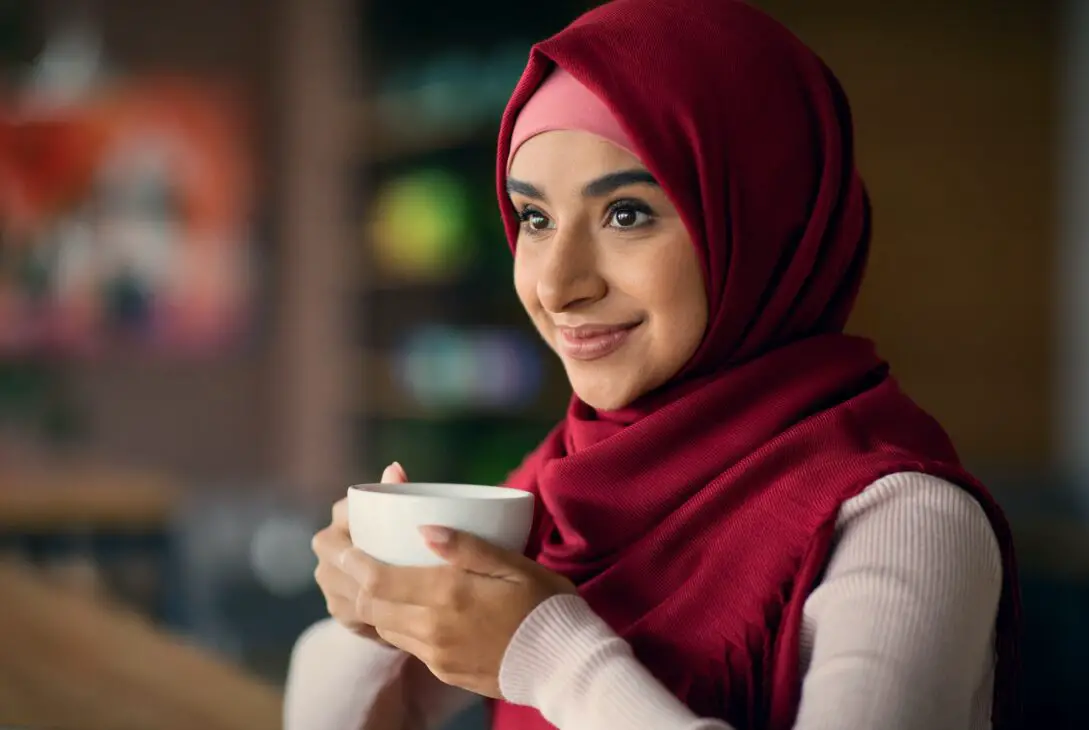 Attractive middle eastern woman in hijab holding coffee mug