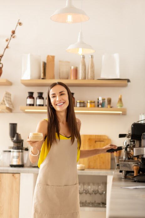 Barista smiling while talking to customer and making coffee