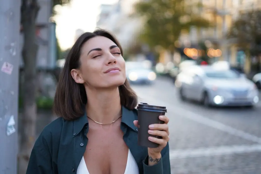 Caucasian woman with cup of coffee outdoor city street happy smiling