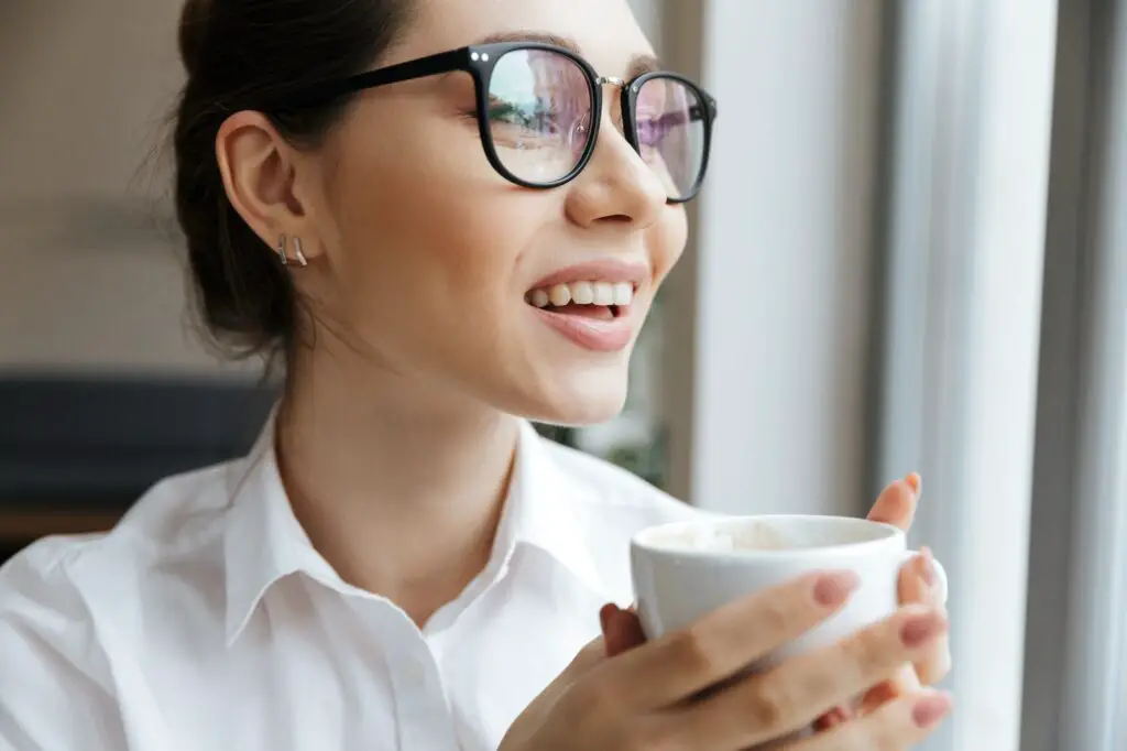 Cheerful business woman sitting indoors drinking coffee. surprising health benefits of drinking coffee