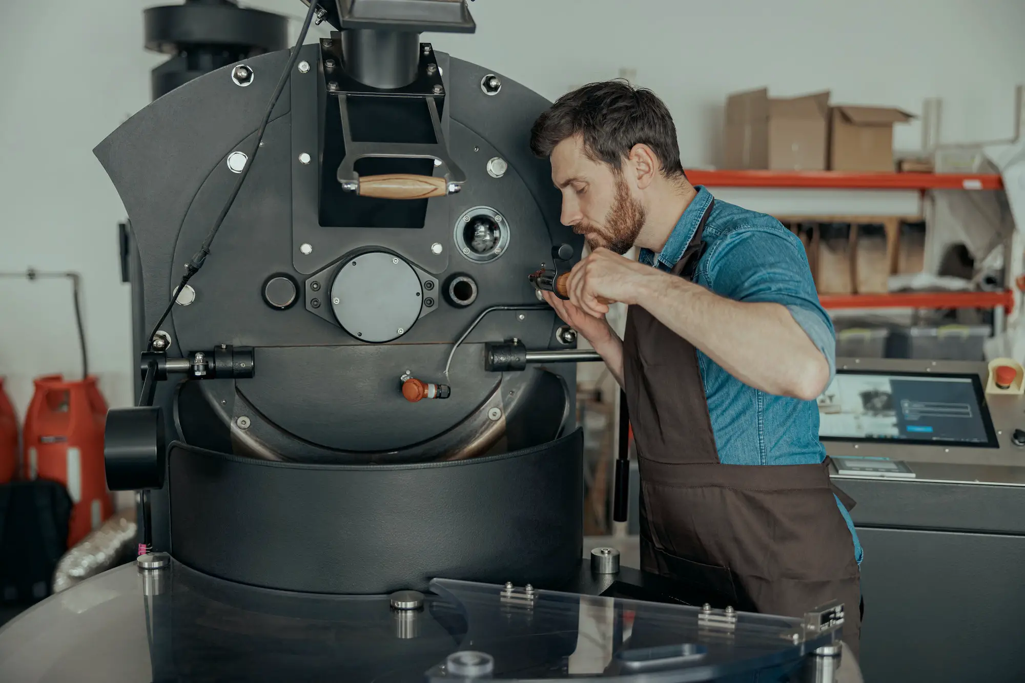 Male worker in uniform repairing a coffee roasting machine