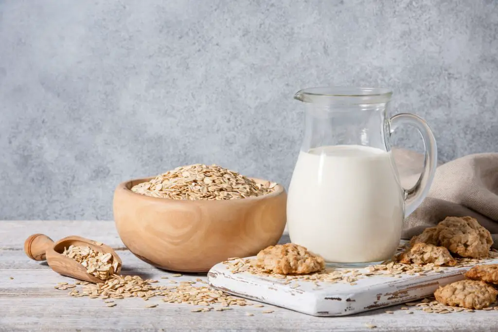 Oat milk, flakes and cookies on wooden table. plant based milk alternative