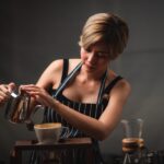 Professional barista preparing and brewing coffee using chemex pour over coffee maker