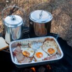 The perfect camping breakfast - bacon, eggs, bread and coffee in billy tin
