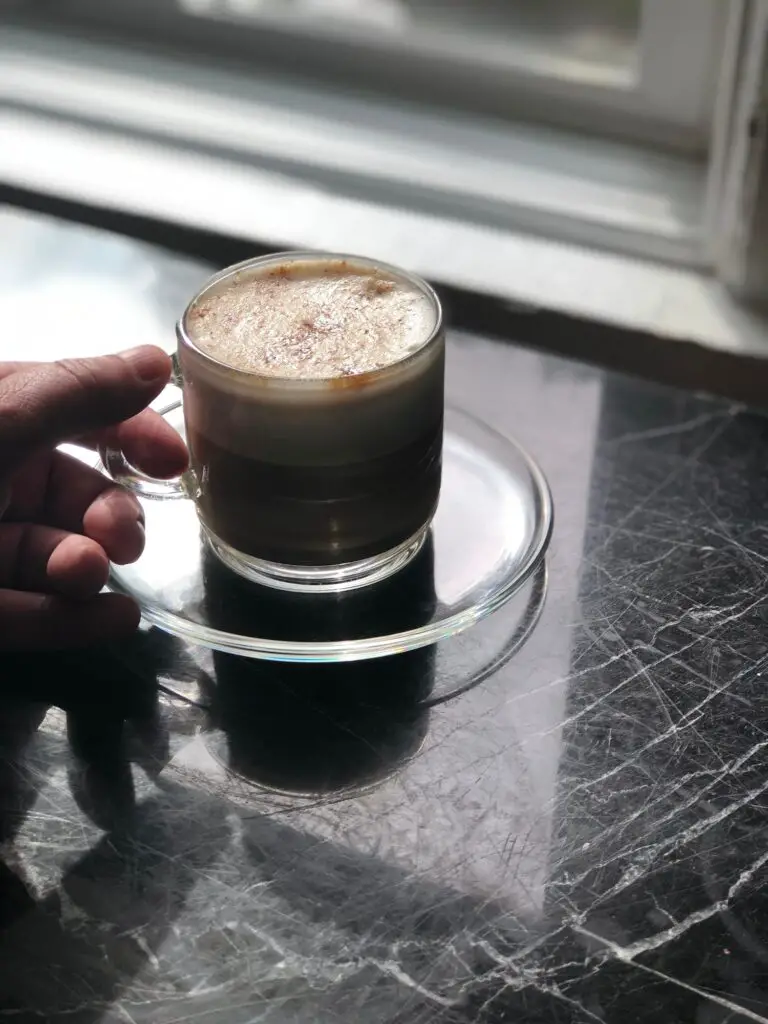 Woman drinking cappuccino near windowsill