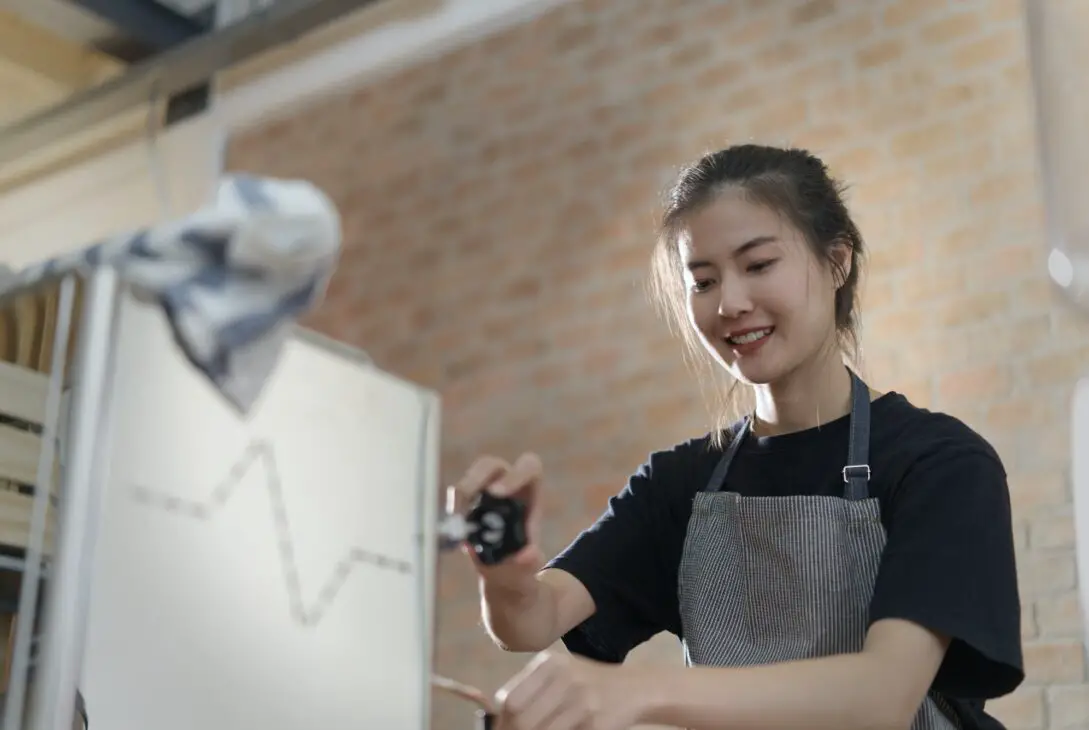 Young cute Asian barista girl making coffee in coffee shop.