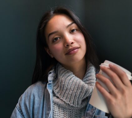 Charming young woman in sweater having coffee