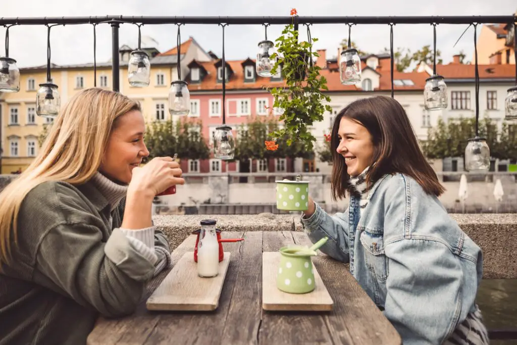 Couple of best friends meeting for a coffee date sitting outside at a cafe in the city center