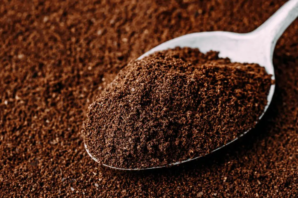 Ground coffee in spoon close-up.