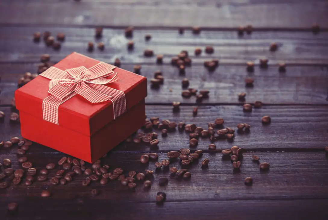 Red gift box and coffee on wooden table.