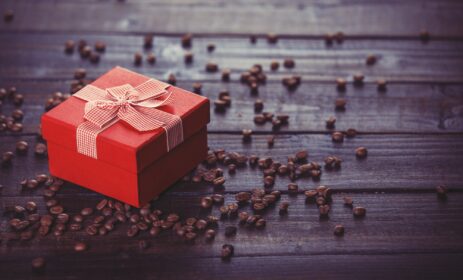 Red gift box and coffee on wooden table.