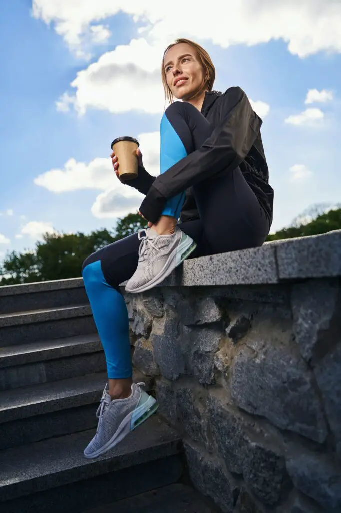 Smiling sportswoman with cup of coffee outdoors